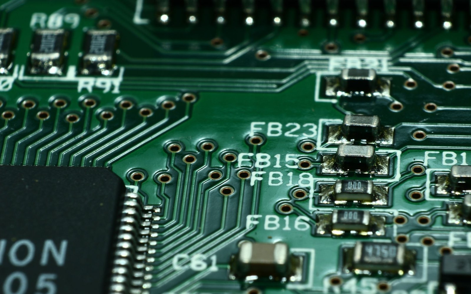 Close-up of a green circuit board showing labeled resistors, capacitors and solder pads